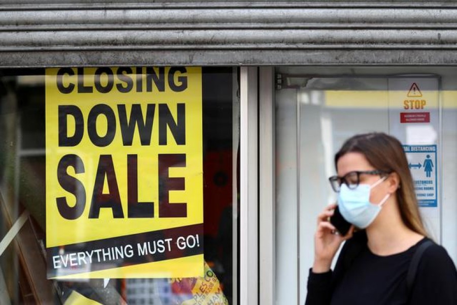 A woman wearing a protective mask speaks on the phone in front of a closed down store, as the spread of the coronavirus disease (COVID-19) continues, in London, Britain July 16, 2020. REUTERS/Hannah McKay/File Photo
