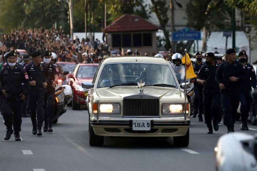 The royal motorcade carrying Thailand's Queen Suthida and Prince Dipangkorn drives past a group of anti-government demonstrators in front of Government House, on the 47th anniversary of the 1973 student uprising, in Bangkok, Thailand October 14, 2020. Picture taken October 14, 2020. REUTERS