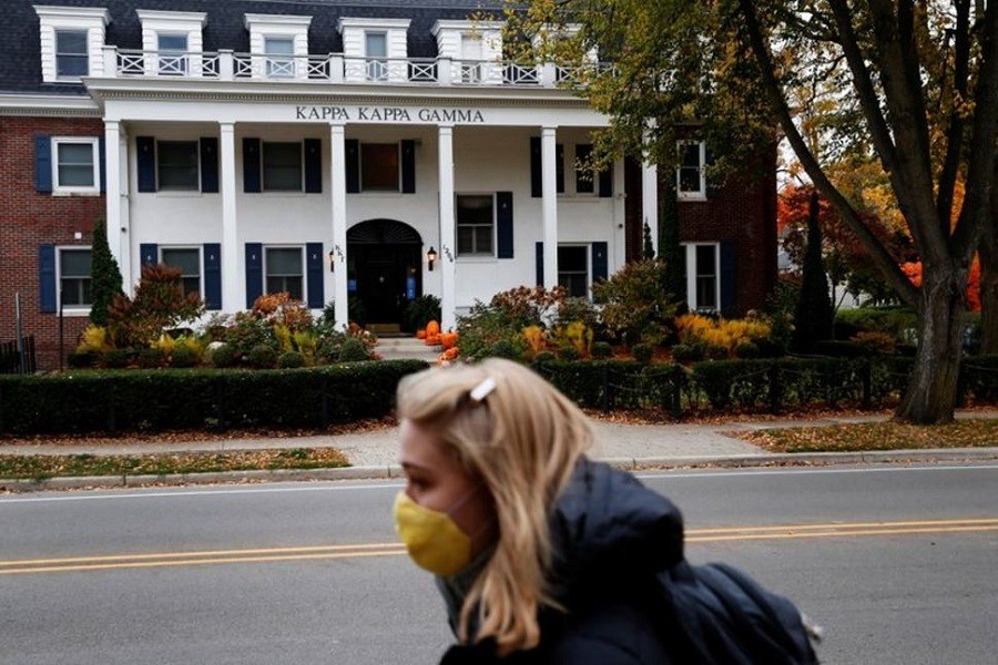 A woman wearing a protective face mask walks past a sorority house on the University of Michigan campus, where state health officials in Michigan issued a stay-in-place order for undergraduate students, in Ann Arbor, Michigan, US, October 26, 2020 — Reuters