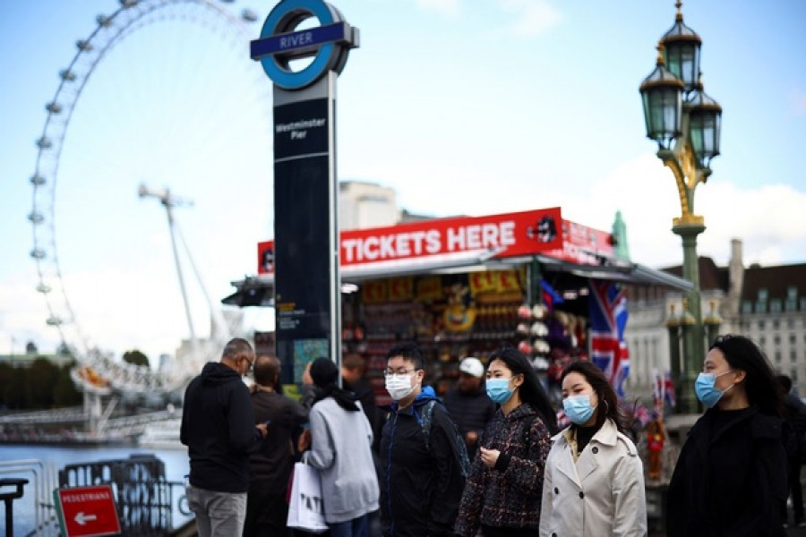 People wearing protective face masks walk across Westminster Bridge, during the coronavirus disease (COVID-19) outbreak, in London, Britain, October 22, 2020. Reuters