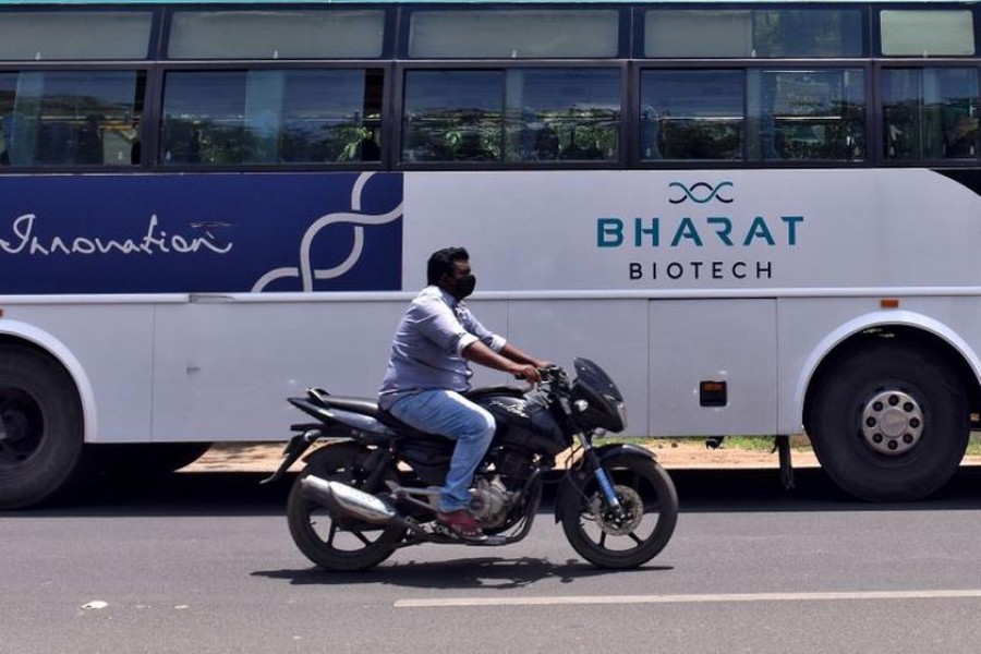 A man rides his motorcycle past a parked bus of Indian biotechnology company Bharat Biotech outside its office in Hyderabad, India on July 3, 2020 — Reuters/Stringer/Files