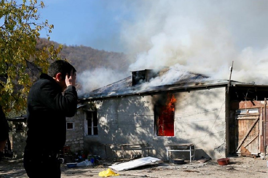 A man reacts as he stands near a house set on fire by departing Ethnic Armenians, in an area which had held under their military control but is soon to be turned over to Azerbaijan, in the village of Cherektar in the region of Nagorno-Karabakh, November 14, 2020 — Reuters