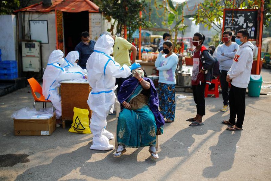 A healthcare worker wearing personal protective equipment (PPE) collects a swab sample from a woman amidst the spread of the coronavirus disease (Covid-19), at Delhi-Uttar Pradesh border, in Noida, India on November 19, 2020 — Reuters photo