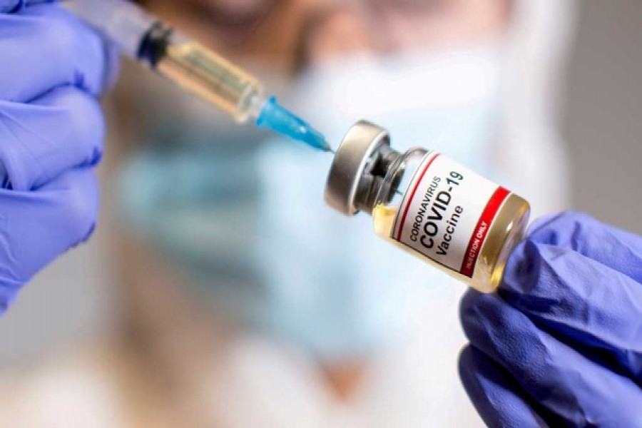 A woman holds a small bottle labeled with a "Coronavirus COVID-19 Vaccine" sticker and a medical syringe in this illustration taken October 30, 2020. Reuters