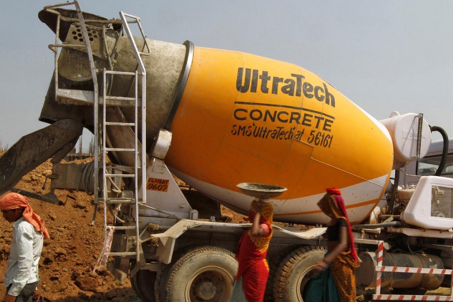 Workers walk in front of an UltraTech concrete mixture truck at the construction site of a commercial complex on the outskirts of the western Indian city of Ahmedabad April 22, 2013. Reuters/ Amit Dave/ File photo