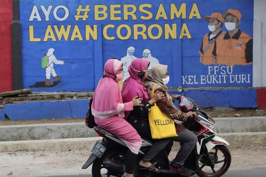 Muslim women are riding a motorbike past a coronavirus-themed mural in Indonesia. Writings on the mural read "Let's fight coronavirus together". The photo was taken in September this year. –AP file photo
