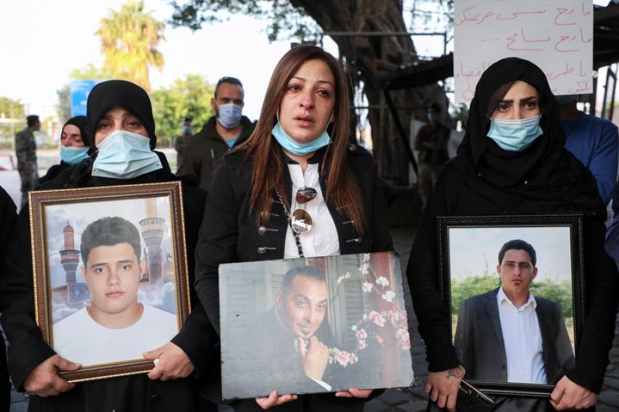 Samia Doughan (C), mother of twin girls, holds a picture of her husband Mohammad, 48, who was killed in the August 4 explosion at the Port of Beirut, as she stands with families of other victims during a protest marking the four-month anniversary since the blast, at the entrance to the Port of Beirut, in Beirut, Lebanon, December 4, 2020 — Reuters/Files
