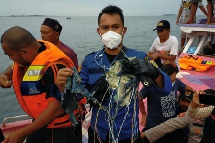 A member of the rescue team looking for an Indonesian plane that lost contact after taking off from the capital Jakarta holds suspected debris, at sea, January 9, 2021, in this picture obtained from social media. INSTAGRAM @HUMASJAKFIRE/via REUTERS