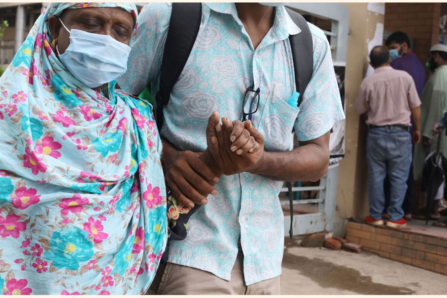 A woman with the support of her son leaving a hospital in Dhaka after giving sample for Covid-19 test       - FE Photo