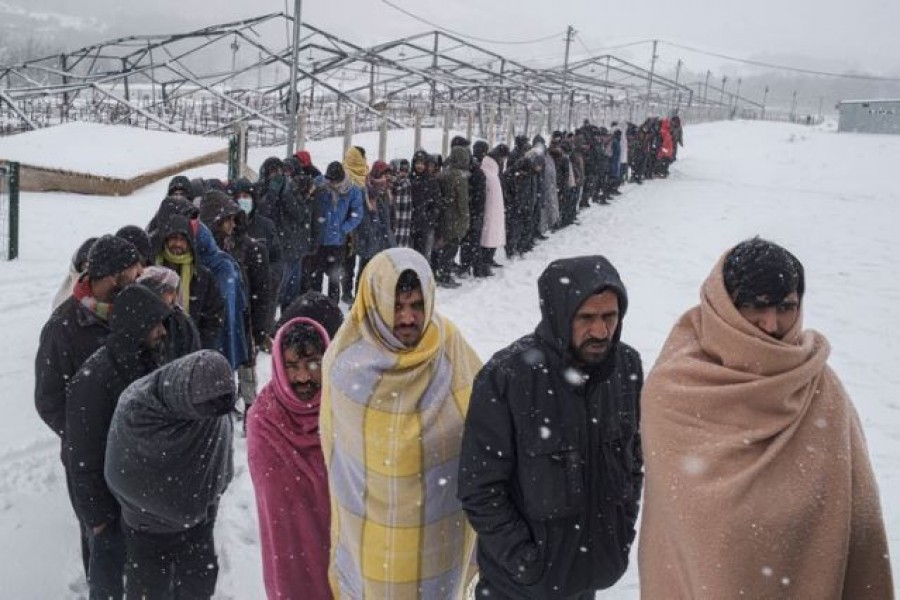 Migrants queue to receive food during a snowfall as hundreds of them are taking shelter in abandoned buildings in the northwestern town of Bihac in Bosnia and Herzegovina, January 11, 2021. REUTERS/Marko Djurica