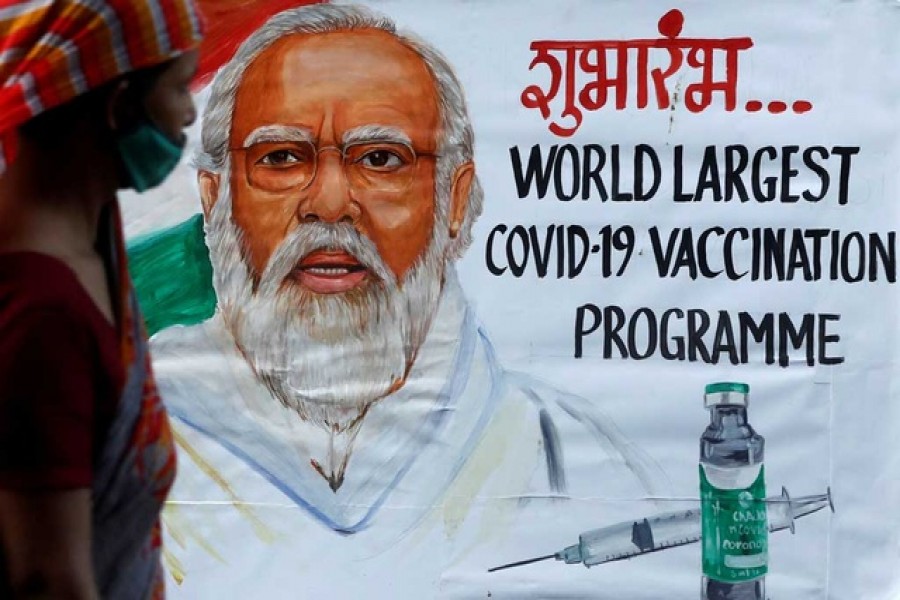 A woman walks past a painting of Indian Prime Minister Narendra Modi a day before the inauguration of the Covid-19 vaccination drive on a street in Mumbai, India, January 15, 2021 — Reuters