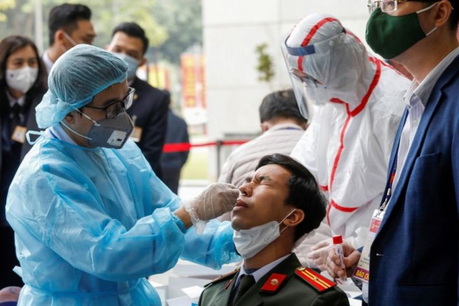 A health worker wearing a protective suit takes a swab sample from a security officer at the National Convention Center, the venue for the 13th National Congress of the Communist Party of Vietnam, during the coronavirus disease (COVID-19) outbreak in Hanoi, Vietnam January 29, 2021. REUTERS
