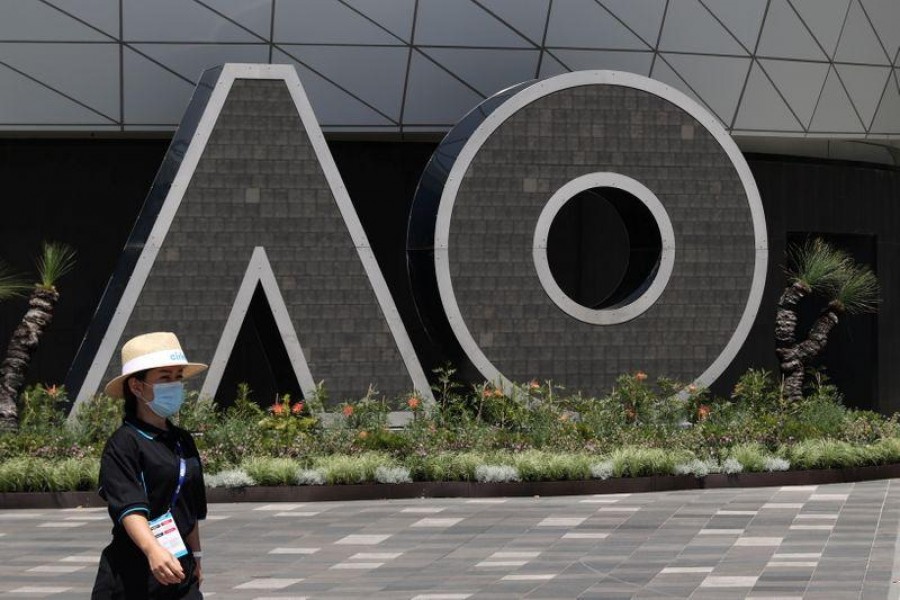 A person wearing a protective face mask walks past an Australian Open logo at Melbourne Park in advance of the tennis tournament, which will start later than usual due to a coronavirus disease (COVID-19) postponement, in Melbourne, Australia, January 31, 2021. REUTERS/Loren Elliott