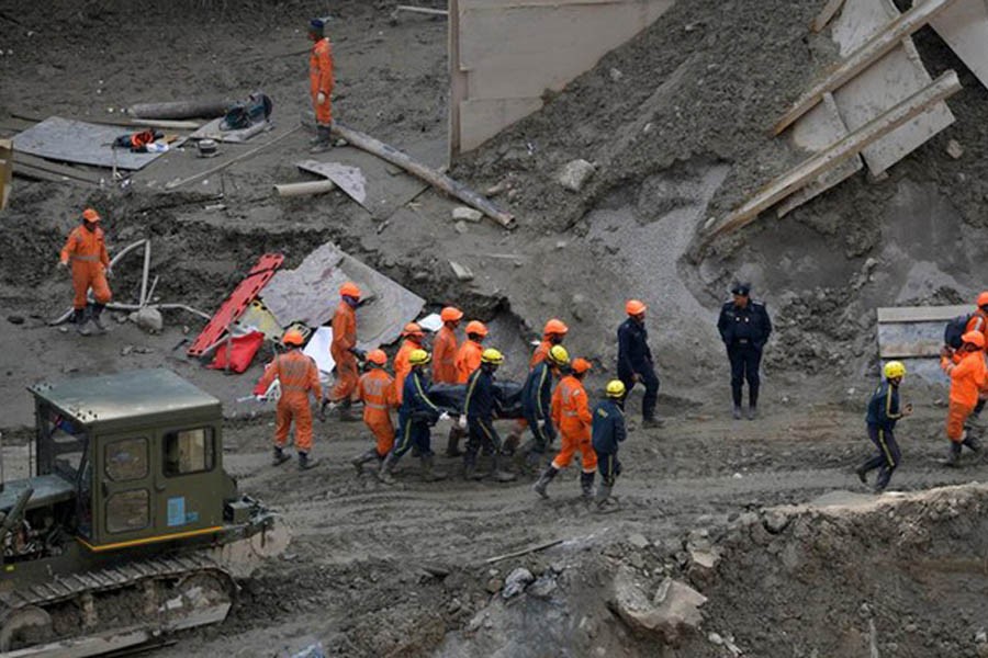 Members of National Disaster Response Force (NDRF) and State Disaster Response Fund (SDRF) carry the body of a victim after recovering it from the debris inside a tunnel during a rescue operation after a flash flood swept a mountain valley destroying dams and bridges, in Tapovan in the northern state of Uttarakhand, India, February 14, 2021. REUTERS