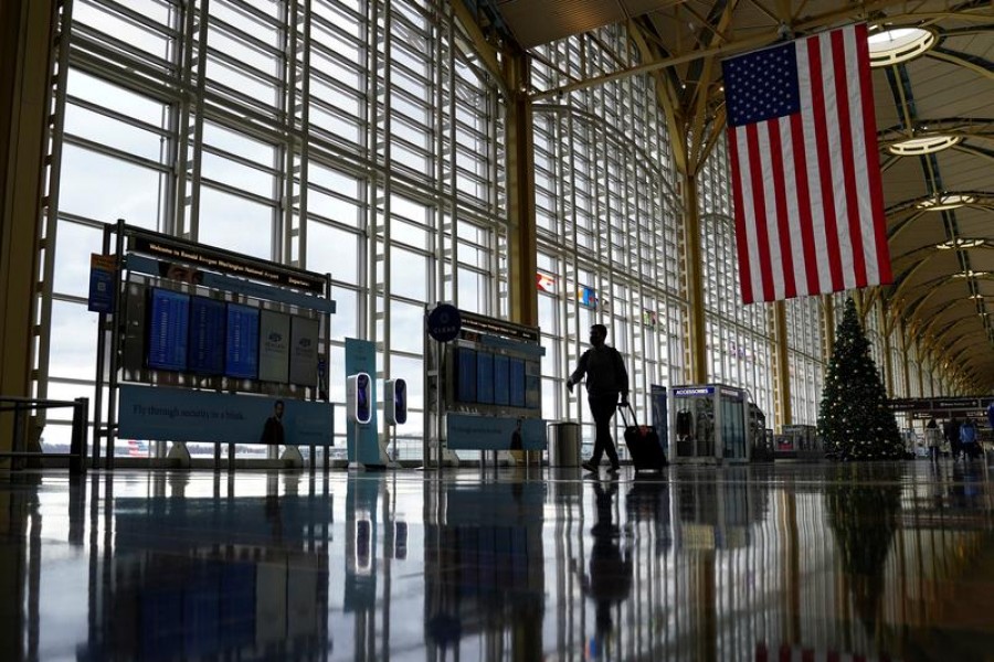 FILE PHOTO: A traveler walks past a Christmas tree as he makes his way through the Ronald Reagan Washington National Airport, in Arlington, Virginia, U.S., December 22, 2020. REUTERS/Kevin Lamarque/File Photo