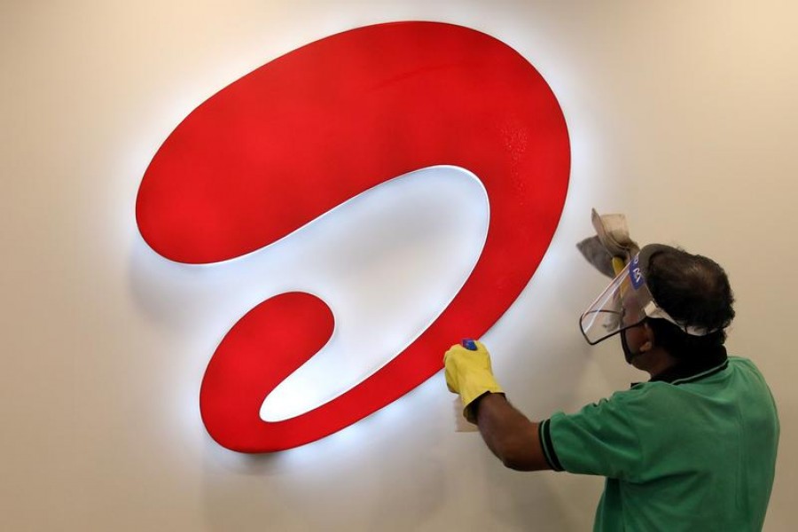 A man wearing a protective face shield cleans a Bharti Airtel logo inside its store in Kolkata, India, July 7, 2020. REUTERS/Rupak De Chowdhuri