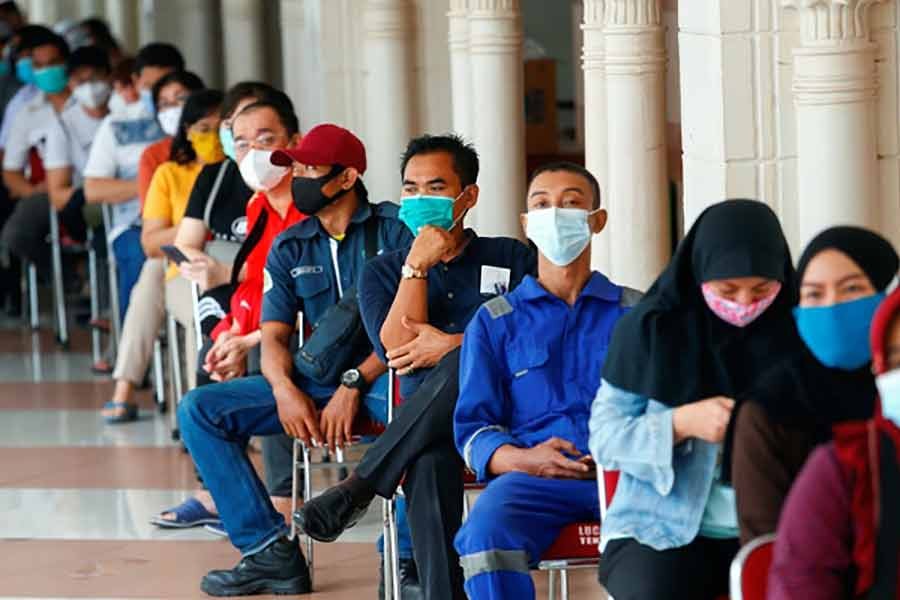 People wearing protective masks sit as they queue before receiving a dose of China's Sinovac Biotech vaccine for the coronavirus disease (COVID-19) at the Tanah Abang textile market in Jakarta of Indonesia on Wednesday -Reuters Photo