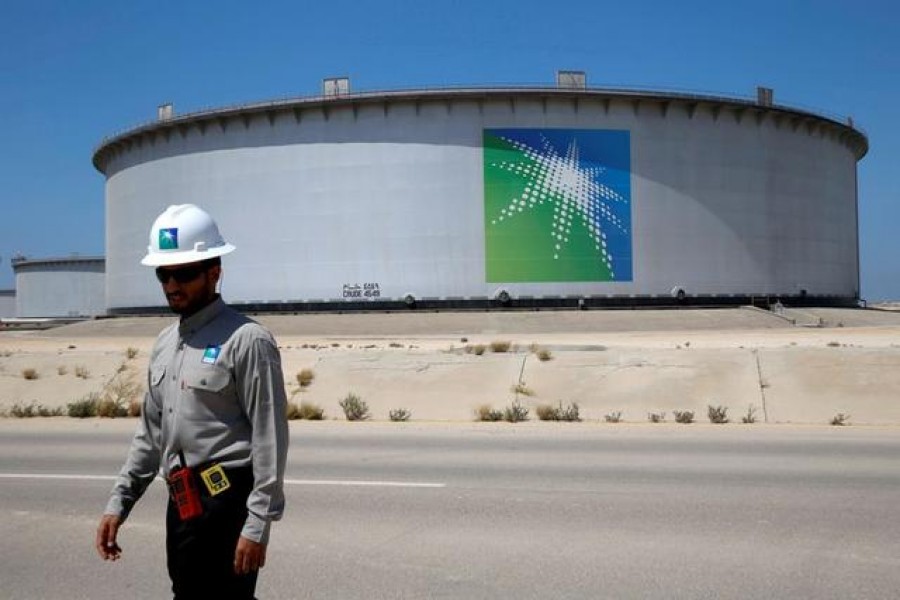 FILE PHOTO: An Aramco employee walks near an oil tank at Saudi Aramco's Ras Tanura oil refinery and oil terminal in Saudi Arabia May 21, 2018. REUTERS/Ahmed Jadallah/File Photo