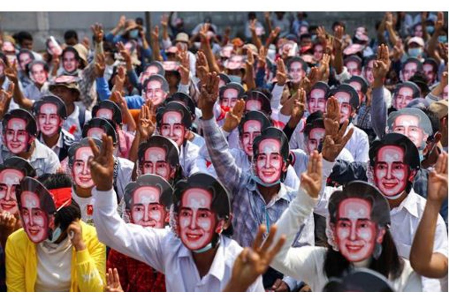 Protesters wearing masks depicting ousted leader Aung San Suu Kyi, flash three-finger salutes as they take part in a protest against the military coup in Yangon, Myanmar, Feb 28, 2021. REUTERS