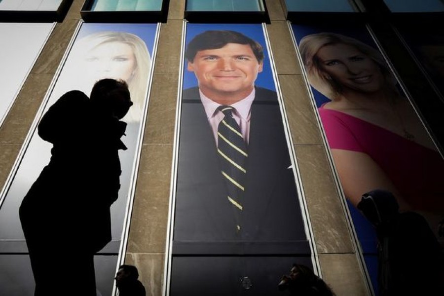 People pass by a promo of Fox News host Tucker Carlson on the News Corporation building in New York, US, March 13, 2019 — Reuters