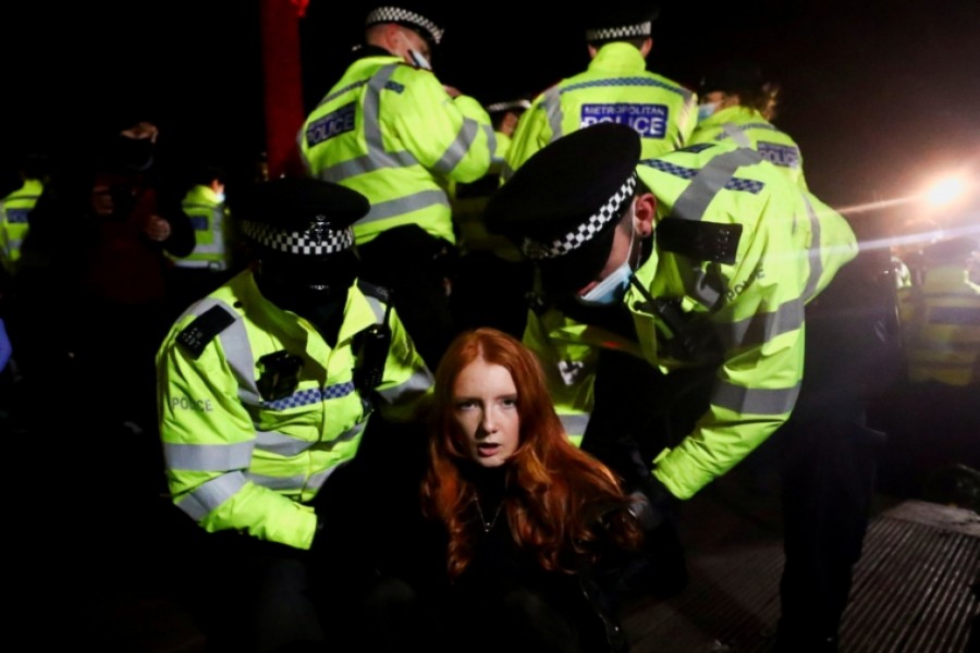 Police detain a woman as people gather at a memorial site in Clapham Common Bandstand, following the kidnap and murder of Sarah Everard, in London, Britain March 13, 2021. REUTERS/Hannah McKay