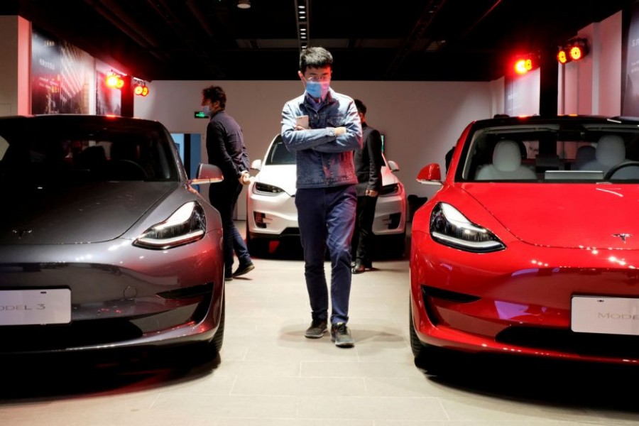 A man wearing a face mask following the coronavirus disease (Covid-19) outbreak walks by Tesla Model 3 sedans and Tesla Model X sport utility vehicle at a new Tesla showroom in Shanghai, China on May 8, 2020 — Reuters/Files