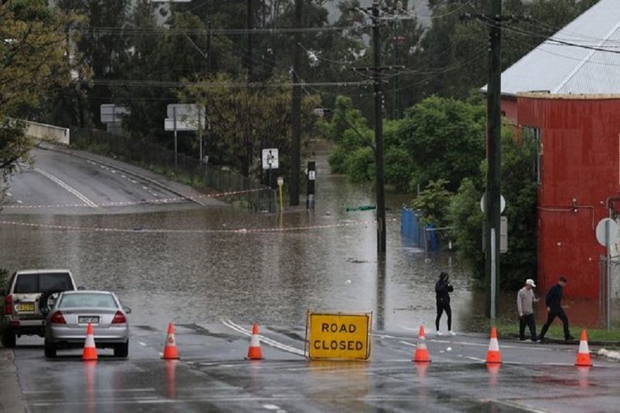 People walk on a street inundated with floodwaters in the suburb of Windsor as the state of New South Wales experiences widespread flooding and severe weather, in Sydney, Australia, March 22, 2021 — Reuters