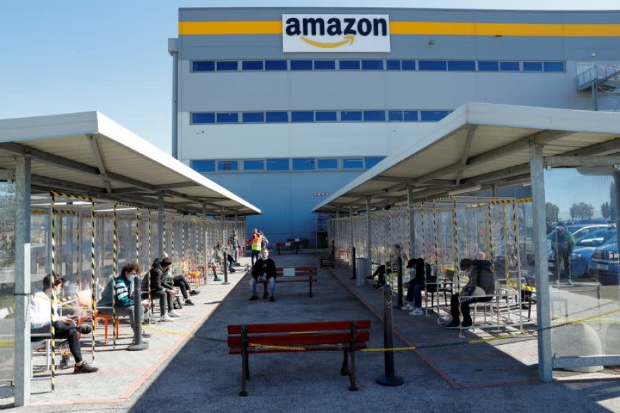 Workers relax during a break outside Amazon's distribution centre in Passo Corese, Italy, March 22, 2021 — Reuters