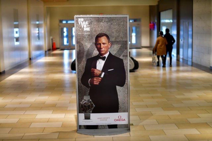 FILE PHOTO: Shoppers walk past an advertisement for the upcoming James Bond film "NO TIME TO DIE" whose release has been delayed due to the coronavirus disease (COVID-19) pandemic, at the Christiana Mall in Newark, Delaware U.S. November 19, 2020. REUTERS/Mark Makela/File Photo