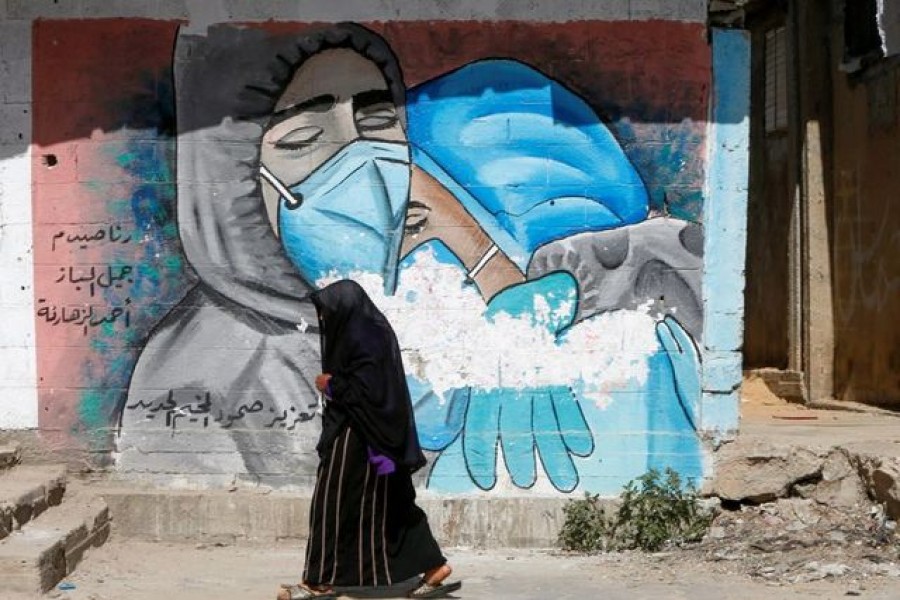 A Palestinian woman walks past a mural, amid the coronavirus disease (Covid-19) outbreak, in the central Gaza Strip on March 17, 2021 — Reuters/Files