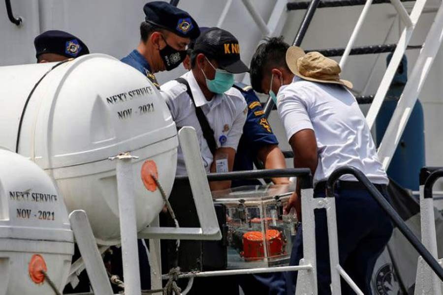 National Transportation Safety Committee (KNKT) officials carry the Cockpit Voice Recorder (CVR) of Sriwijaya Air flight SJ 182 down a flight of stairs on an Indonesian Sea And Coast Guard vessel as it arrives at Tanjung Priok Port in Jakarta, Indonesia, March 31, 2021 — Reuters