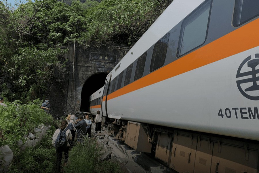 People walk next to a train which derailed in a tunnel north of Hualien, Taiwan on April 2, 2021, in this handout image provided by Taiwan's National Fire Agency — Handout via REUTERS