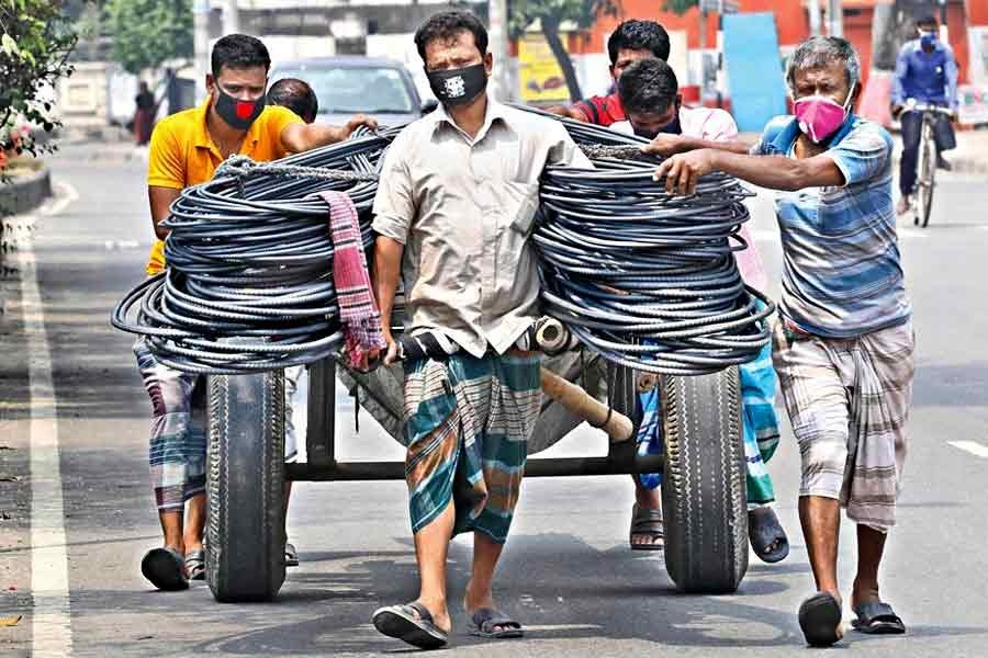 Labourers carrying iron rods by a push-cart, amid the coronavirus (Covid-19) outbreak, at Tejgaon in Dhaka city last year —FE file photo