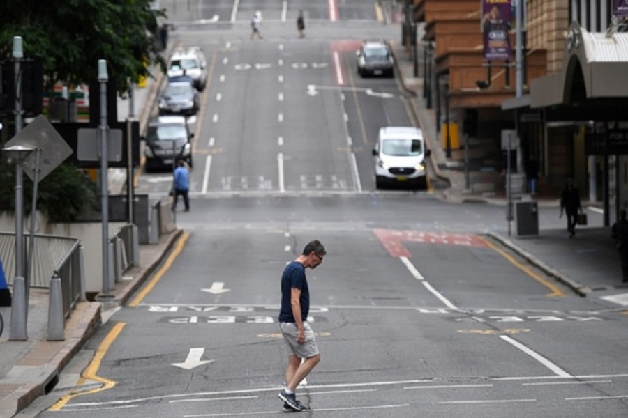 A man crosses a mostly empty city centre street as people in Greater Brisbane have been ordered into lockdown as authorities try to suppress a growing coronavirus disease (COVID-19) cluster in Brisbane, Australia, Mar 30, 2021. REUTERS