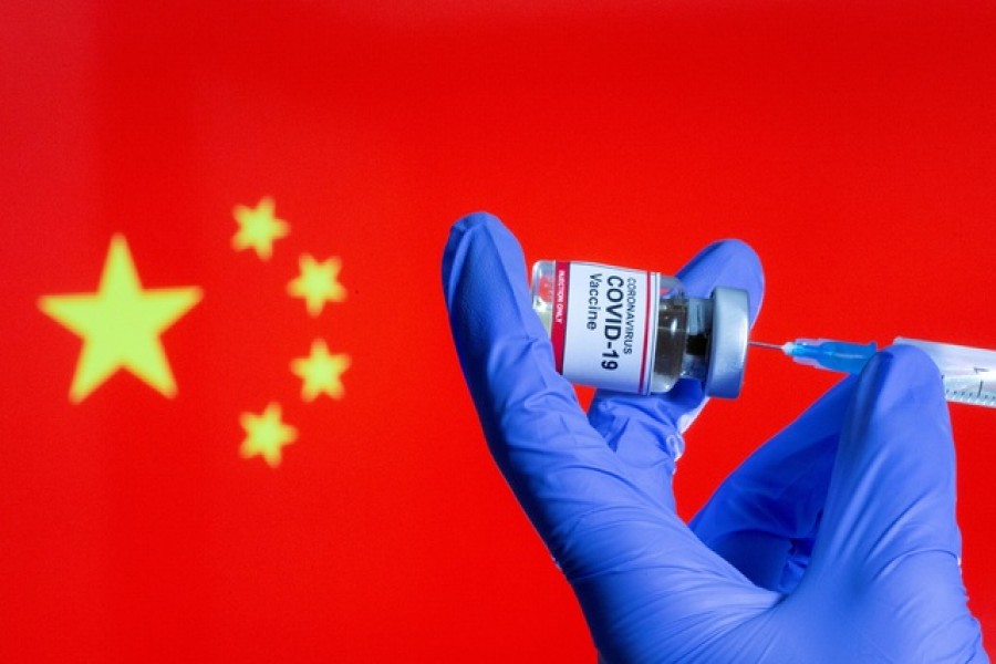 A woman holds a small bottle labeled with a "Coronavirus COVID-19 Vaccine" sticker and a medical syringe in front of displayed China flag in this illustration taken, October 30, 2020 — Reuters/Files