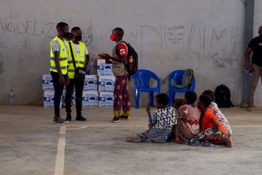 People, who fled an attack claimed by Islamic State-linked insurgents on the town of Palma, look on as aid workers consult a person at a displacement centre in Pemba, Mozambique, April 2, 2021. REUTERS/Emidio Jozine