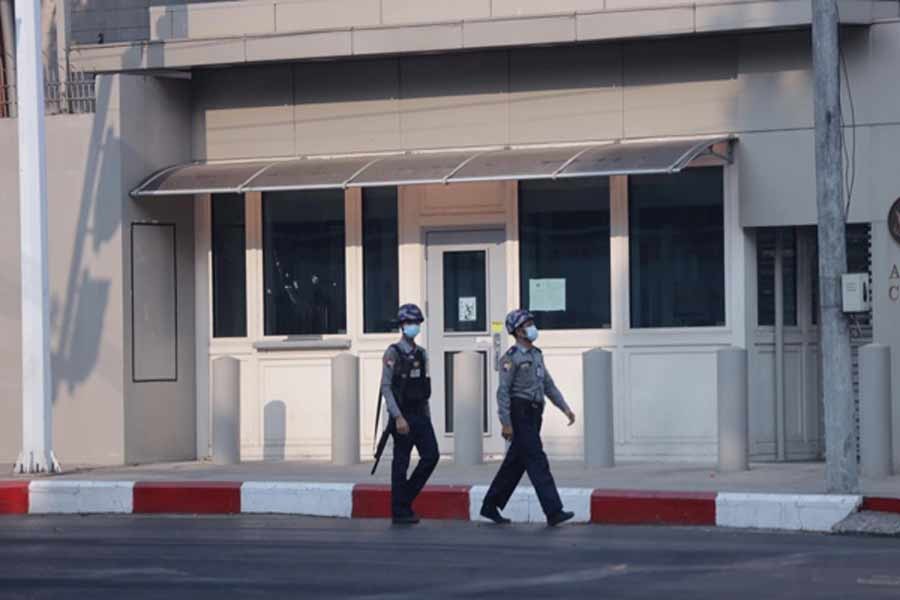 Police officers walking past the bullet holes seen on the window at American Center Yangon (ACY) in Myanmar last month -Reuters file photo