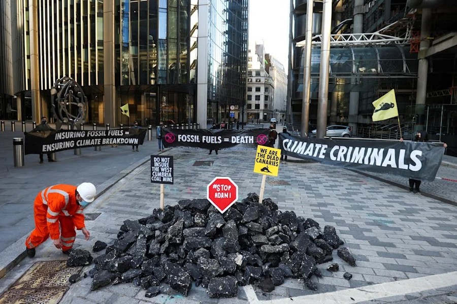 Activists from Extinction Rebellion, a global environmental movement, hold banners as they stand next to fake coal, made from rocks, during a protest outside the Lloyd's building in London — Reuters photo