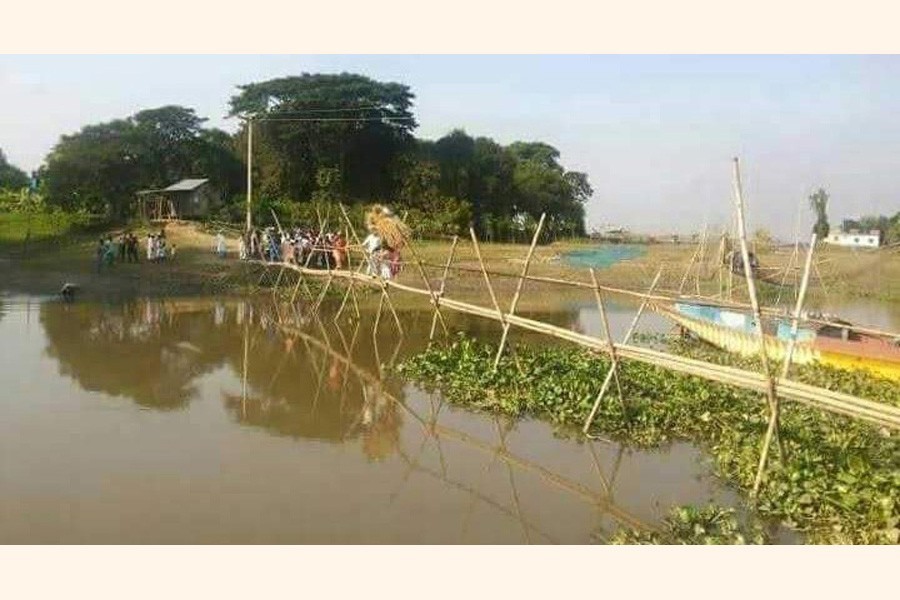 Photo shows people crossing the Kaonal river in Goral village of Asma union in Netrakona's Barhatta upazila through makeshift bamboo bridge — FE Photo