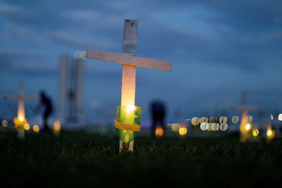 A candle and cross symbolising the ones who died from the coronavirus disease (COVID-19) are seen in front of the National Congress in Brasilia, Brazil Apr 27, 2021. REUTERS