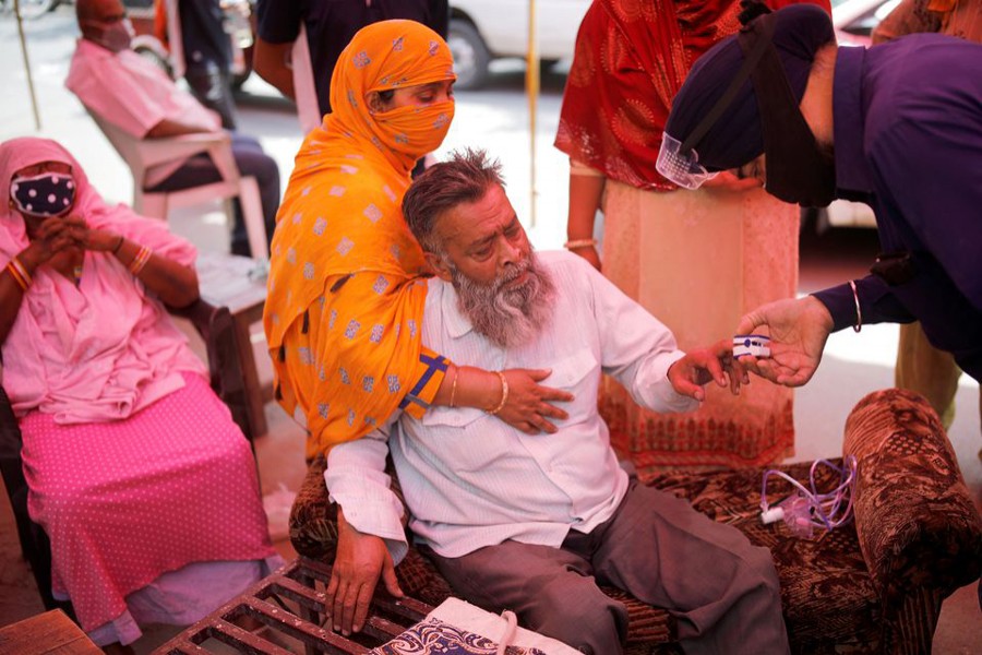 A volunteer uses a pulse oximeter to check the oxygen saturation of a man's blood before providing him oxygen support for free at a Gurudwara (Sikh temple), amidst the spread of coronavirus disease (Covid-19), in Ghaziabad, India on May 3, 2021 — Reuters photo