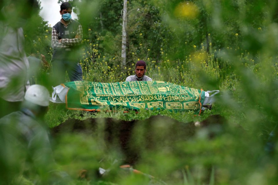 Relatives are seen next to the body of a man who died due to the coronavirus disease (Covid-19), as they wait for a grave to be prepared for his burial at a graveyard on the outskirts of Srinagar on May 4, 2021 — Reuters photo