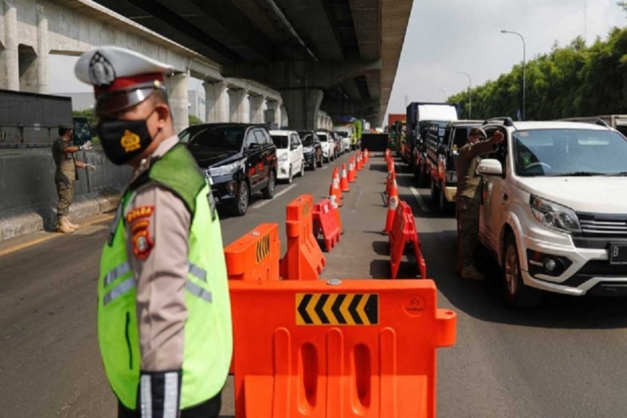 Police and municipality officers guard at a checkpoint on the first day of a national travel ban as Indonesia halts sea, land, air, and rail travel for the Eid-ul-Fitr celebrations in an effort to prevent a large-scale transmission of the coronavirus disease (COVID-19) pandemic, in Karawang, West Java province, May 6, 2021. REUTERS