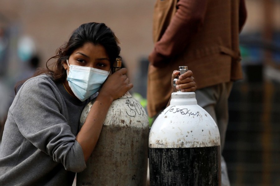 A woman holds on to the oxygen cylinders for a patient after refiling them at a factory, amidst the spread of coronavirus disease (Covid-19) surge as India's outbreak spreads across South Asia, in Kathmandu, Nepal on May 9, 2021 — Reuters photo