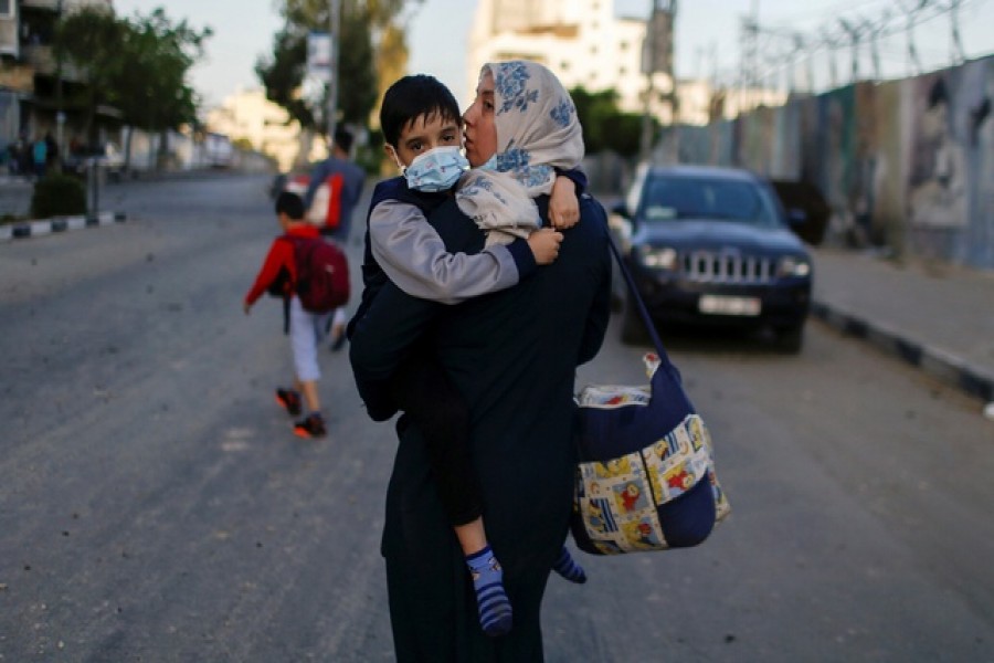 A Palestinian woman carrying her son evacuates after their tower building was hit by Israeli airstrikes, amid a flare-up of Israeli-Palestinian violence, in Gaza City, May 12, 2021 - Reuters photo