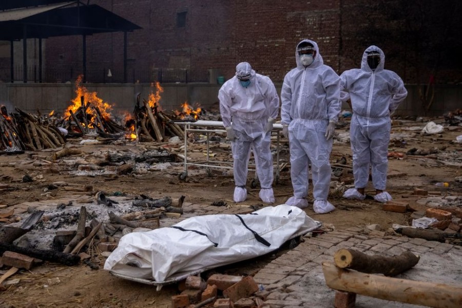 Family members stand next to the body of their relative, who died from the coronavirus, before her cremation at a crematorium ground in New Delhi on May 14 — Reuters photo