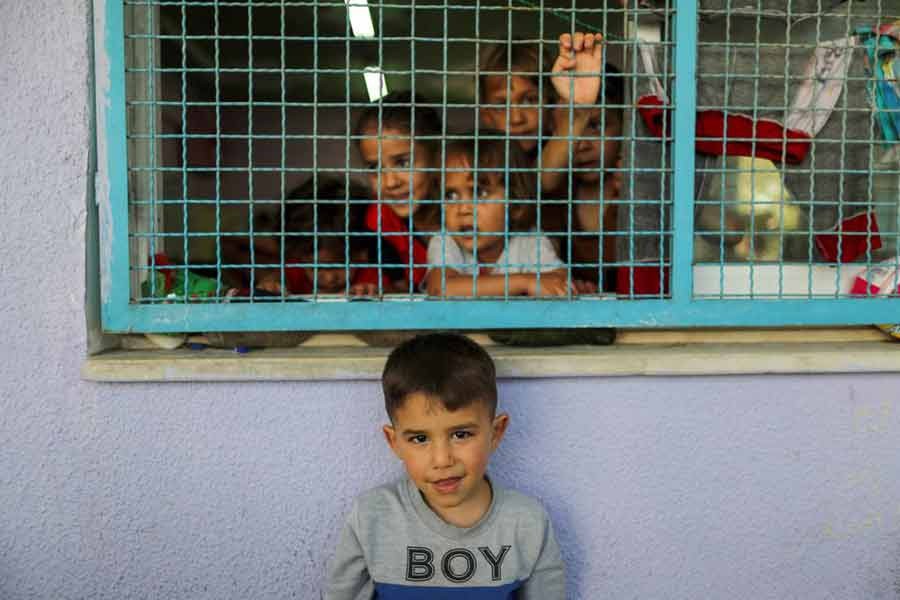 A Palestinian boy, who fled his family's home due to Israeli air and artillery strikes, looking on as other children look through a window fence at a United Nations-run school where they take refuge, in Gaza City on Tuesday –Reuters photo