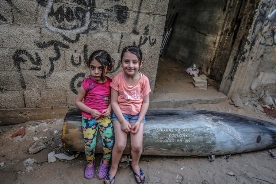 Palestinian sisters sit on an unexploded missile fired by Israeli warplanes in Gaza - EPA photo