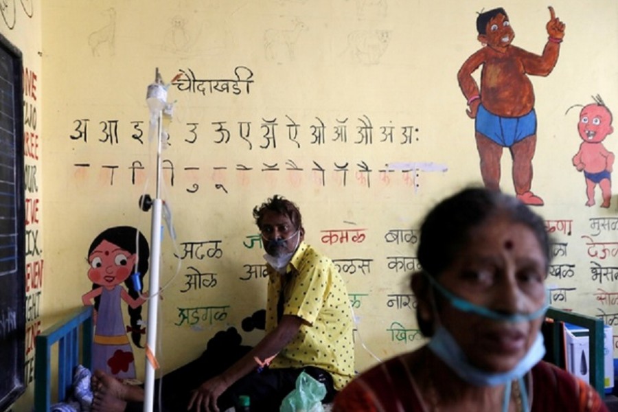 Patients suffering from coronavirus disease (COVID-19) receive oxygen support as they sit inside a classroom turned COVID-19 care facility on the outskirts of Mumbai, India, May 24, 2021. REUTERS