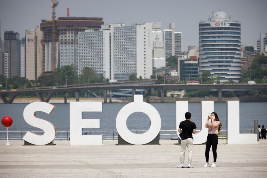 A woman wearing a mask amid the coronavirus disease (Covid-19) pandemic takes photographs of her boyfriend at a Han river park in Seoul, South Korea on May 24, 2021 — Reuters photo